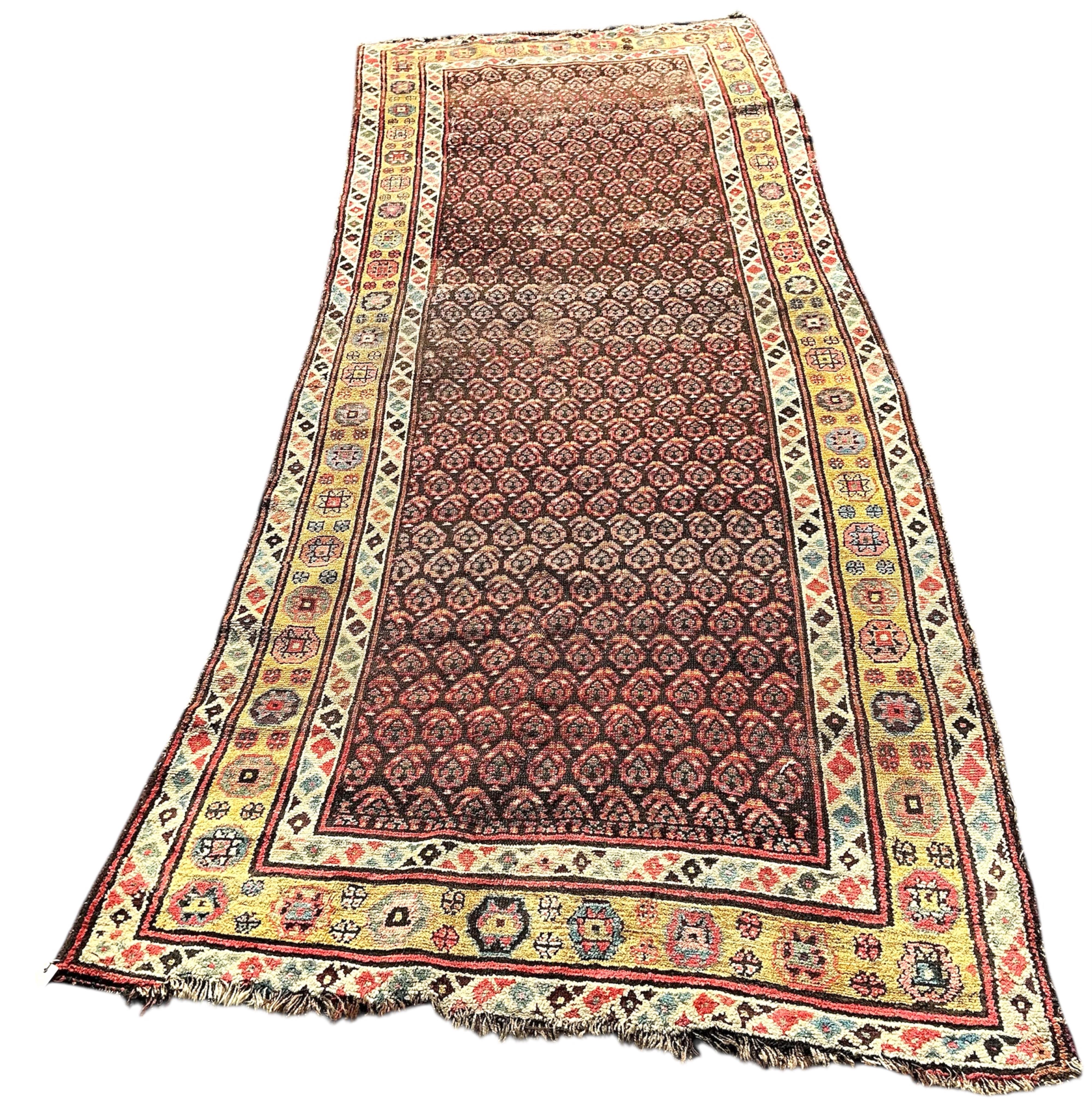An antique Senneh red ground hall carpet, 325 x 128cm